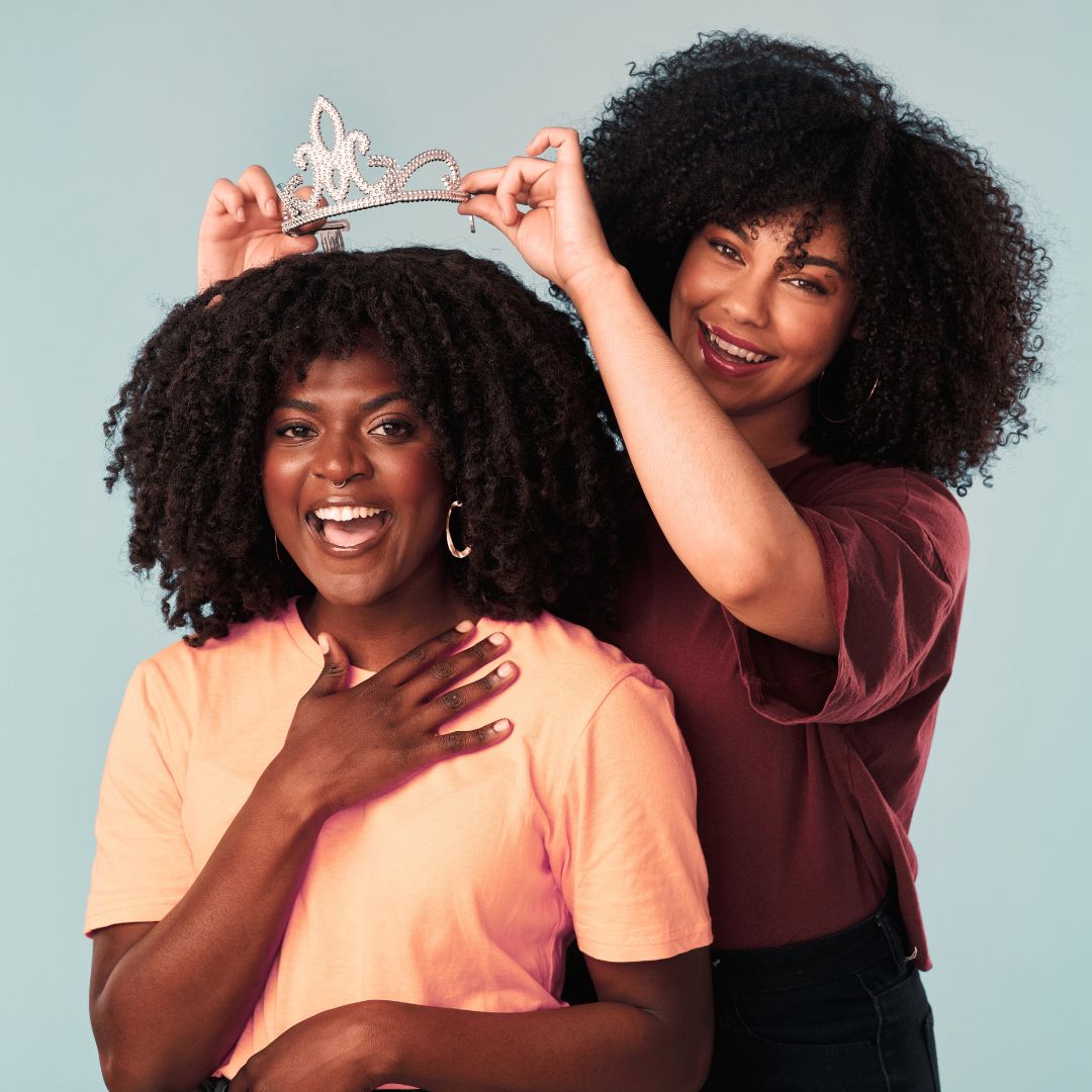 Une femme métissée qui couronne une autre femme, les deux sourient